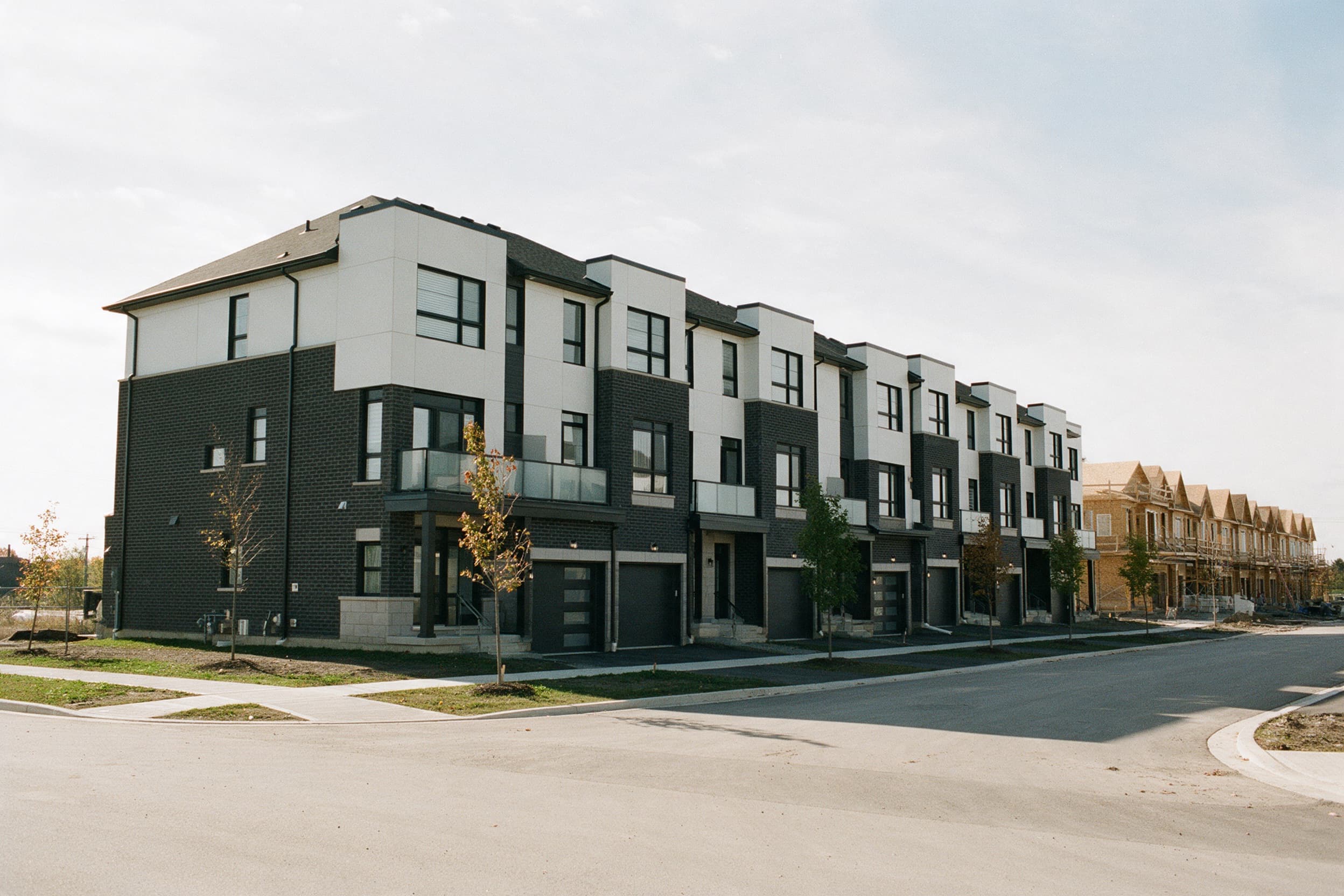 Contemporary freehold townhomes in charcoal brick and white panels on a new Heritage Heights street