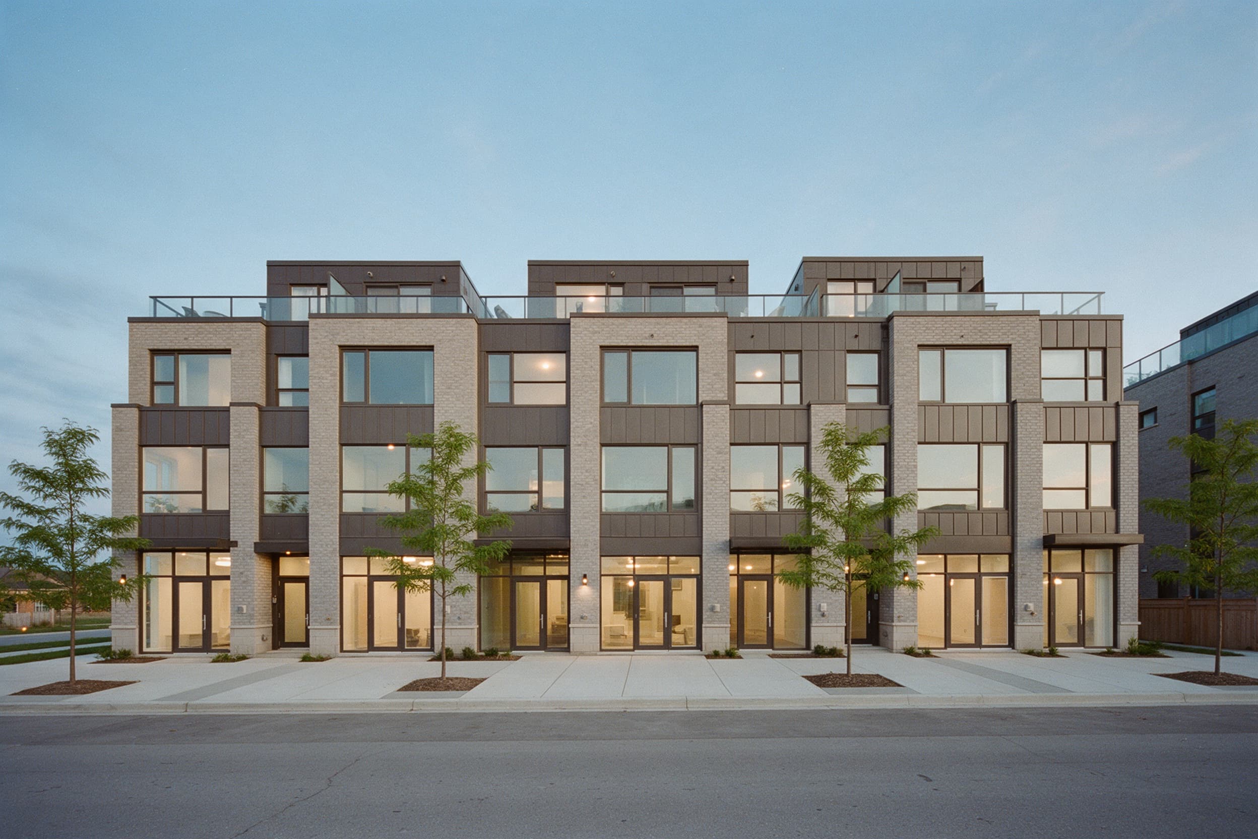 Three-storey urban townhomes with live/work storefronts at dusk