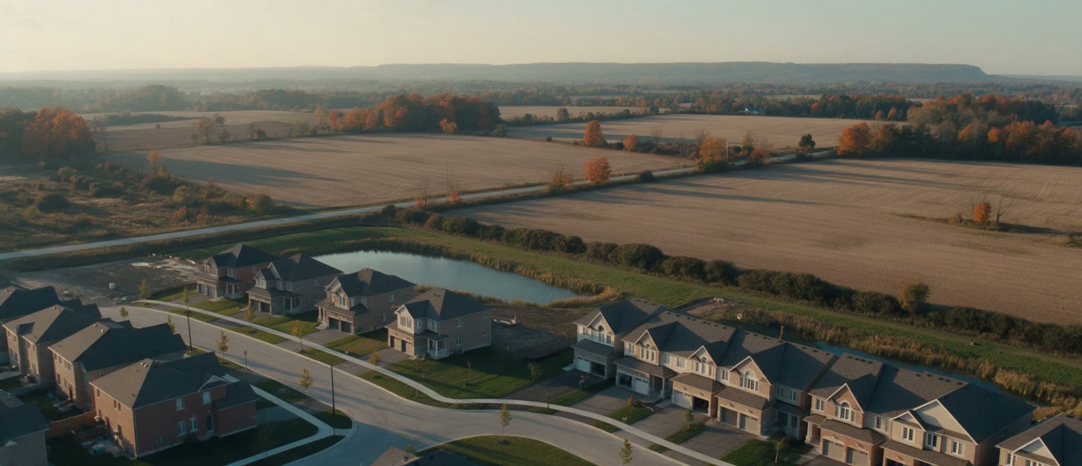 Aerial view of a new subdivision meeting farm fields at golden hour